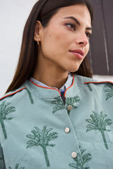 Chaqueta color azqua con bordado de palmeras y ribete a contraste anaranjado.